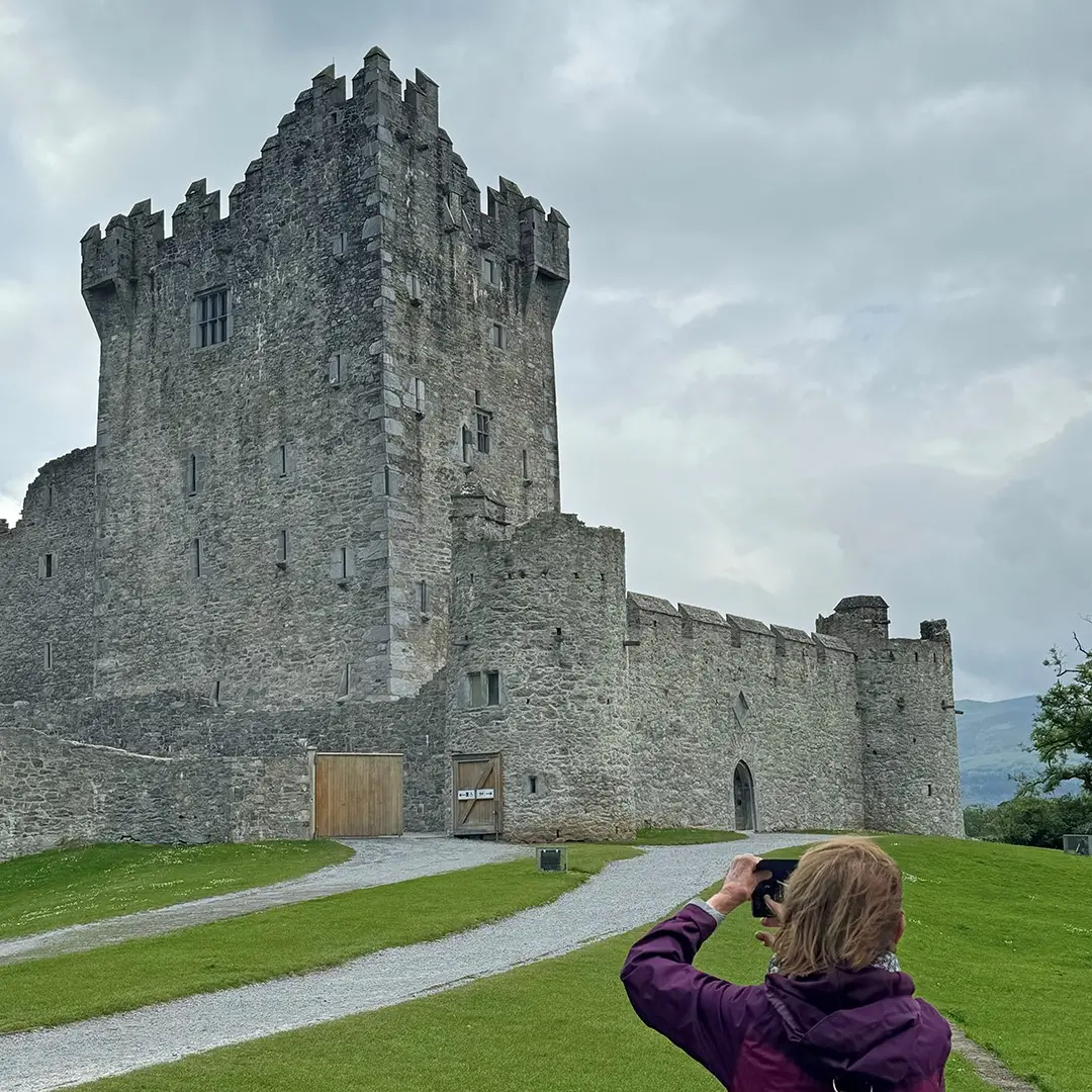 Woman taking photo of Ross Castle in Killarney